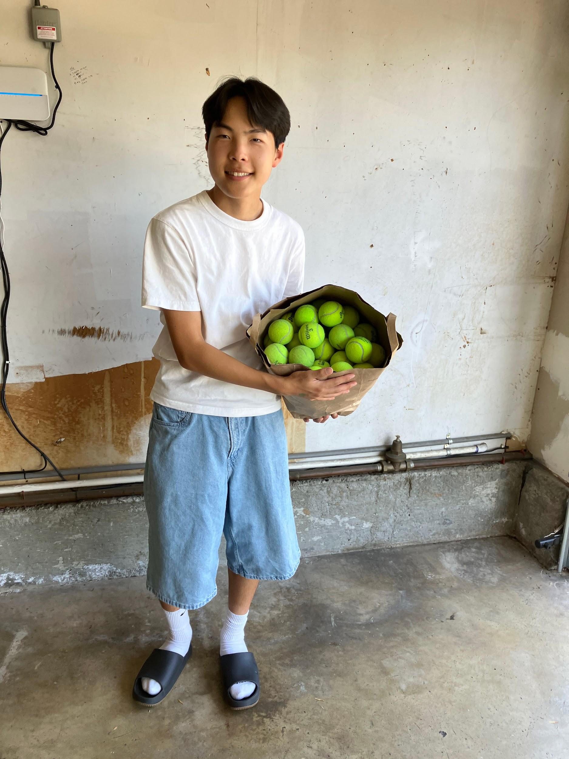 Trevor holding a bag of donated tennis balls from Coach Rick